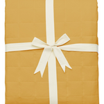 Quilted bamboo blanket in a Marigold yellow folded and tied with ribbon