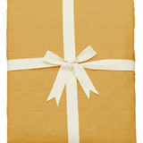 Quilted bamboo blanket in a Marigold yellow folded and tied with ribbon