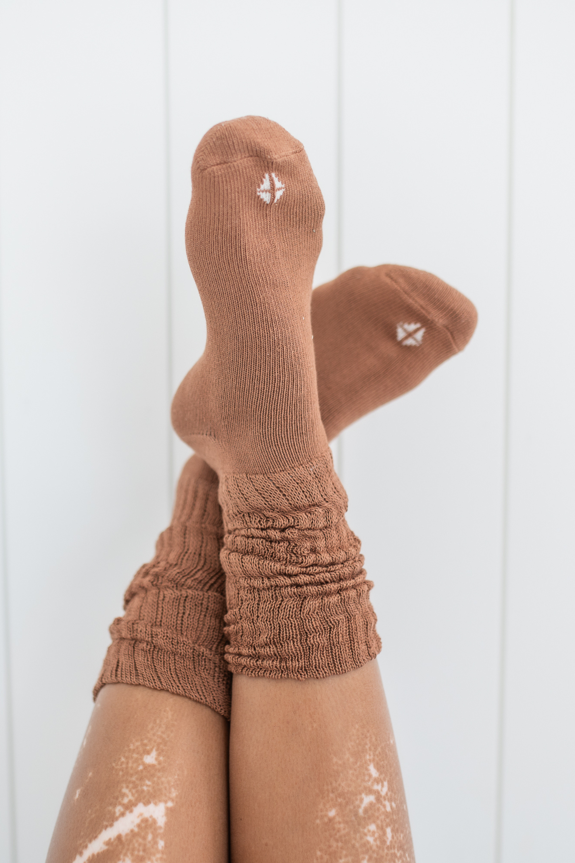 Woman modeling scrunched crew socks in a medium brown color against a white backdrop