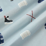 A repeating, all-over print featuring a dark blue hockey jersey with the numbers 00, a pair of crossed brown hockey sticks with a black hockey puck, a white hockey goal, and a pair of black hockey skates, over a light dusty blue background