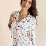 Close up of Model wearing Long-Sleeved Women's Pajama Set in Vanilla Mahjong print with brown trim on a beige background
---PJ 2