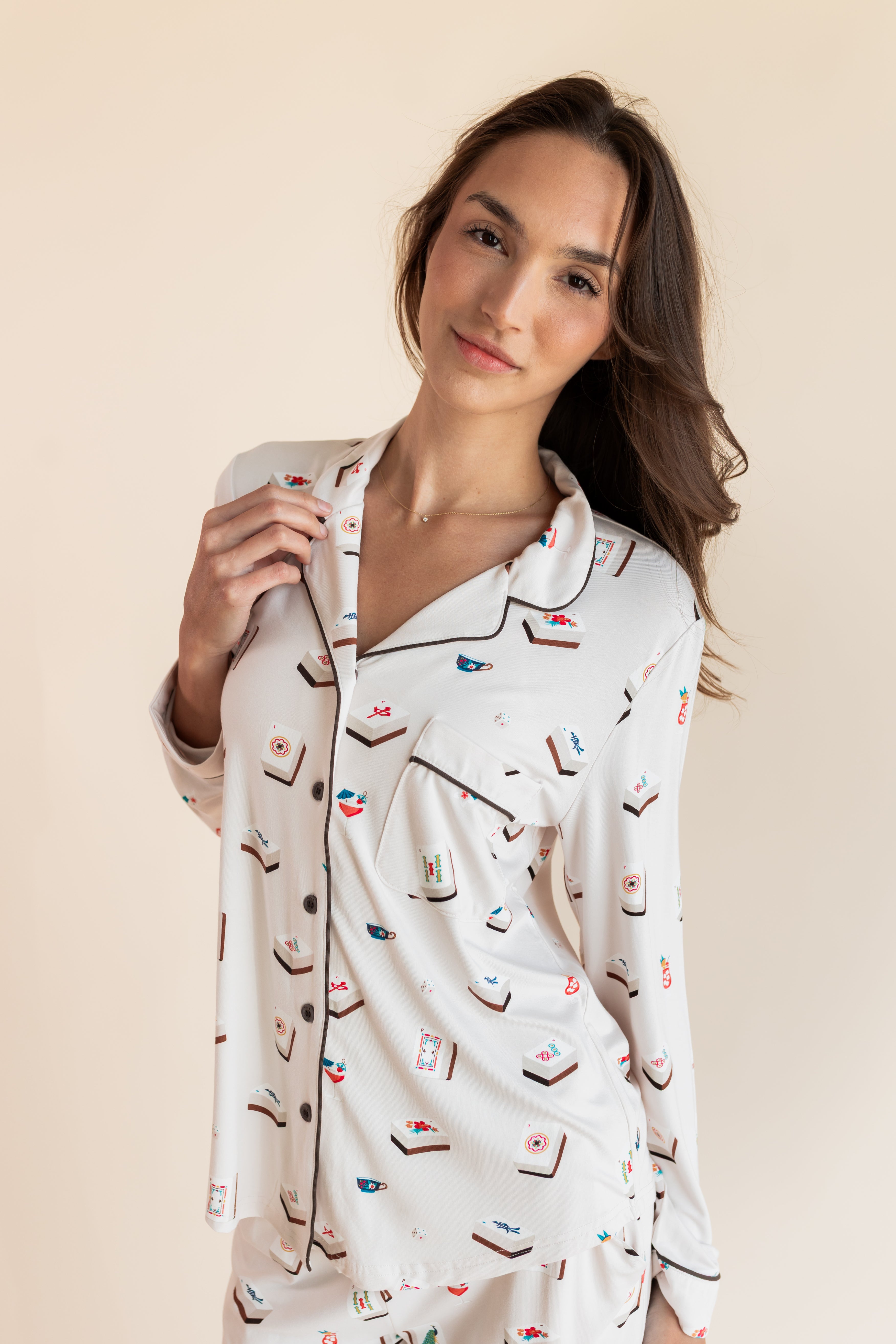 Close up of Model wearing Long-Sleeved Women's Pajama Set in Vanilla Mahjong print with brown trim on a beige background
---PJ 2