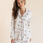 Model smiling in Long-Sleeved Women's Pajama Set in Vanilla Mahjong print with brown trim on a beige background