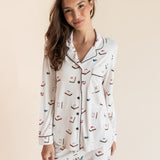 Model smiling in Long-Sleeved Women's Pajama Set in Vanilla Mahjong print with brown trim on a beige background