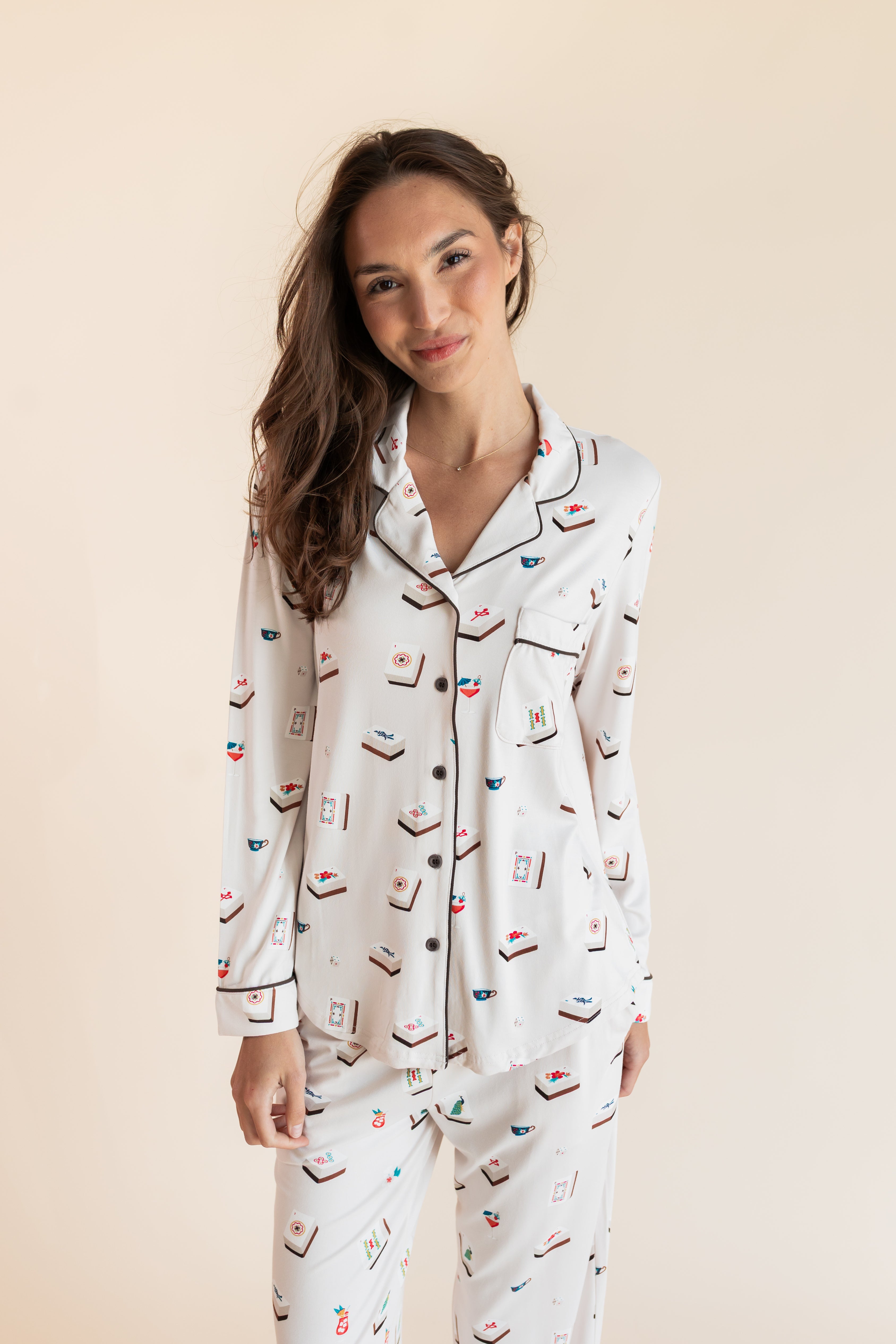 Model smiling in Long-Sleeved Women's Pajama Set in Vanilla Mahjong print with brown trim on a beige background