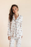 Model smiling in Long-Sleeved Women's Pajama Set in Vanilla Mahjong print with brown trim on a beige background