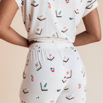 Model showcasing backside of Women's Short Sleeve Cropped Pajama Set in Vanilla Mahjong print on a beige background
