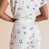 Model showcasing backside of Women's Short Sleeve Cropped Pajama Set in Vanilla Mahjong print on a beige background