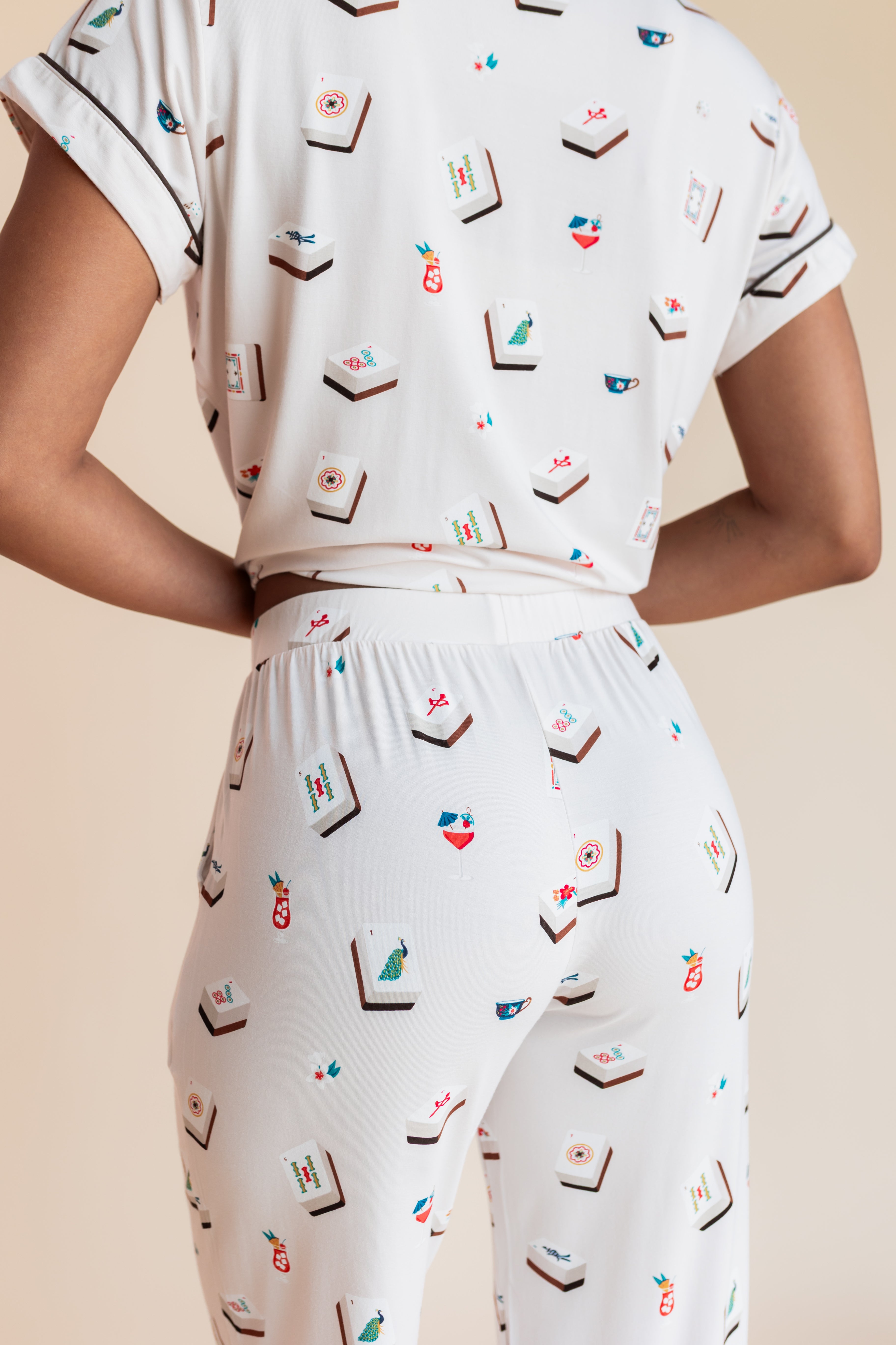 Model showcasing backside of Women's Short Sleeve Cropped Pajama Set in Vanilla Mahjong print on a beige background