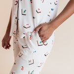 Model showcasing pockets on Women's Short Sleeve Cropped Pajama Set in Vanilla Mahjong print on a beige background