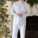 Male model standing with his hands clasped in front of him with a white brick fireplace behind him wearing the Men's Jogger Set in Vintage Santa