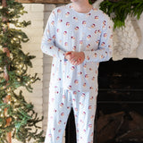 Male model standing with his hands clasped in front of him with a white brick fireplace behind him wearing the Men's Jogger Set in Vintage Santa