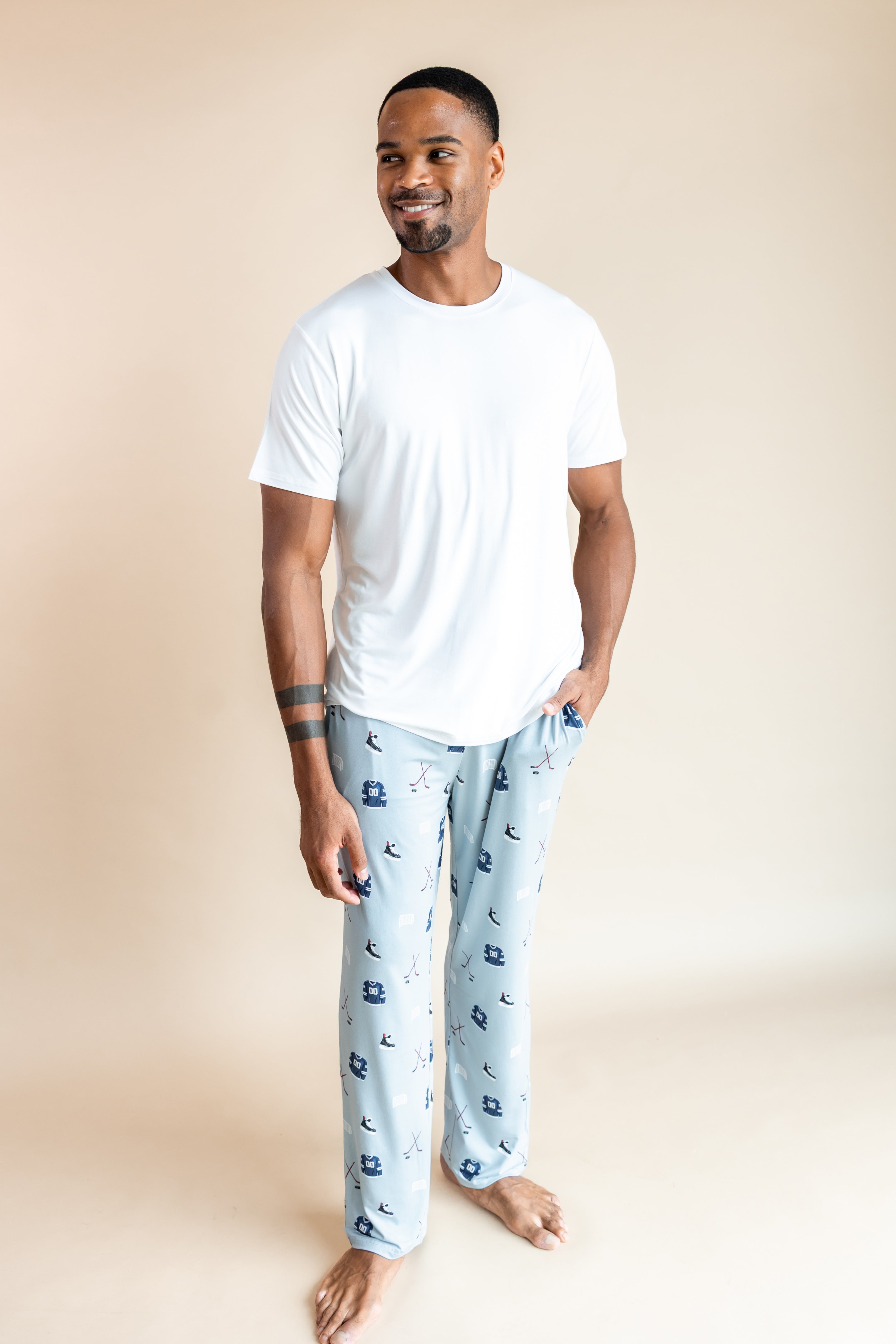 Man posing in Men's Lounge Pants in Vintage Hockey print under white T-shirt on a beige background

