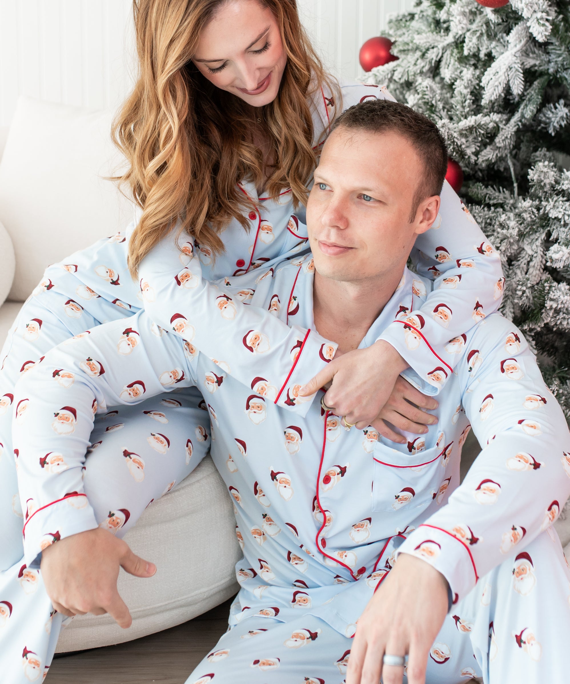 Two people wearing matching pajamas with a Christmas tree in the background