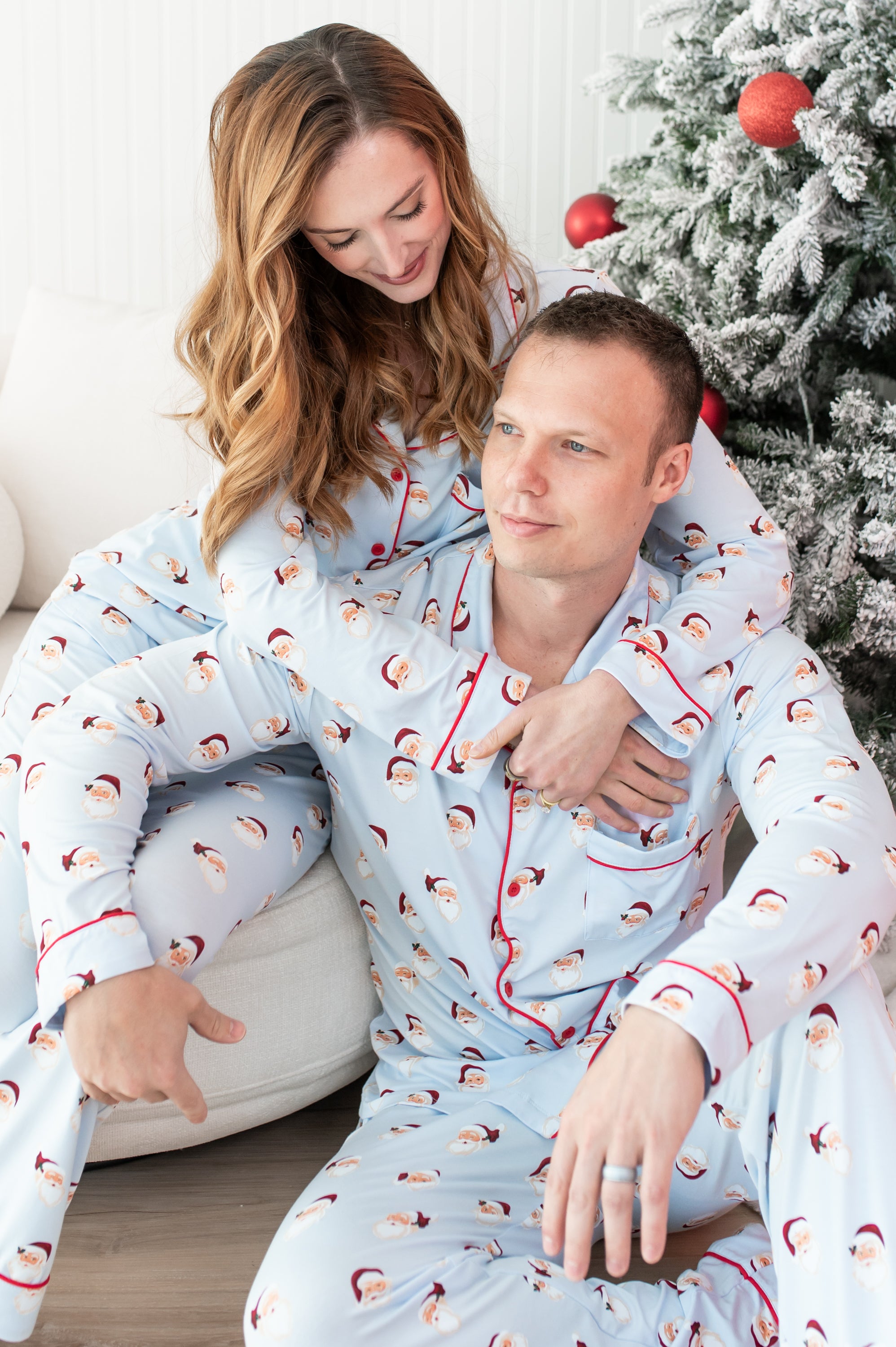 Two people wearing matching pajamas with a Christmas tree in the background