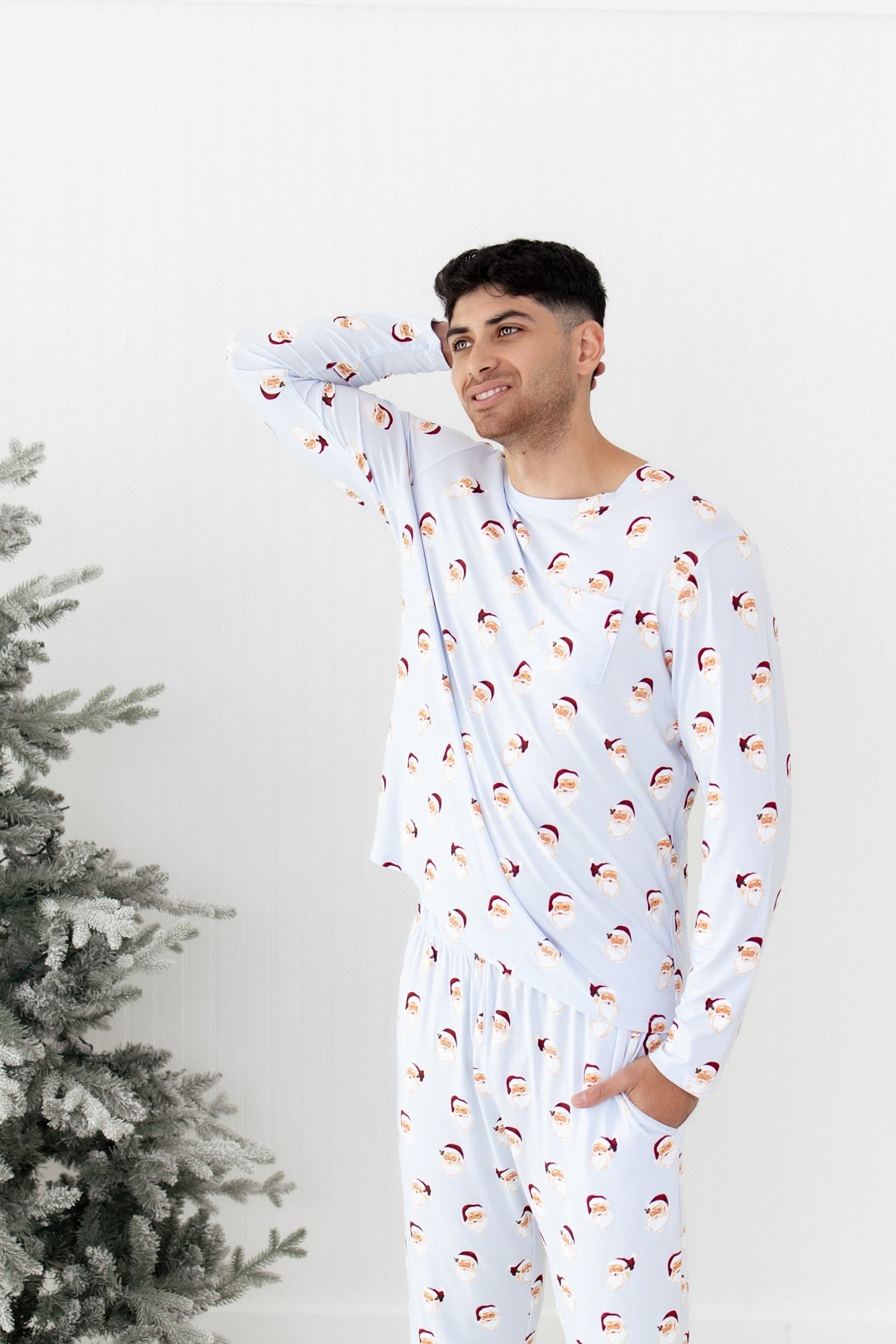 Male model standing looking off to the side with one hand behind his head and the other in the pants pocket of the Men's Jogger Set in Vintage Santa