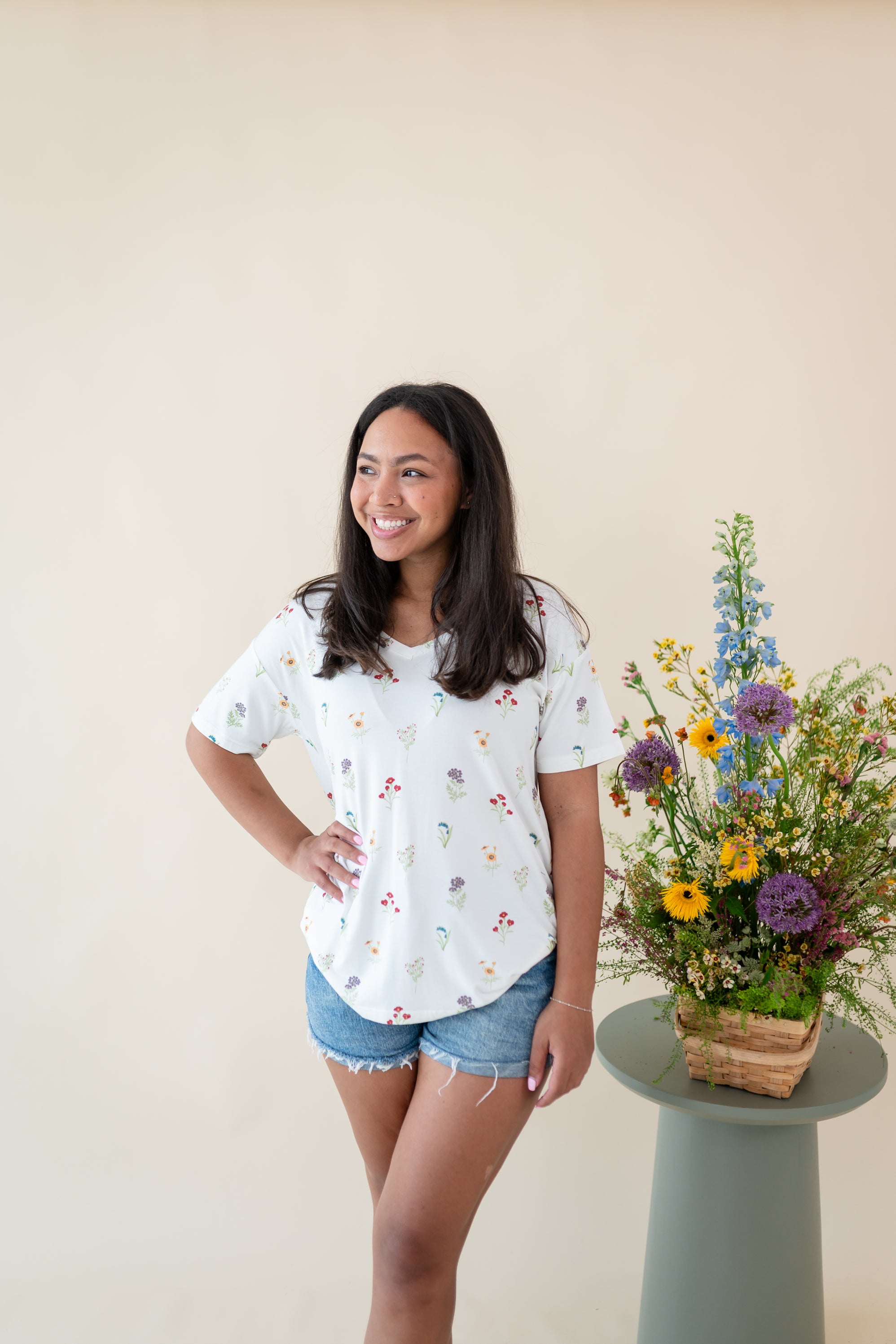 Woman modeling Women’s Relaxed Fit V-Neck in Wildflower next to a floral arrangement 