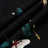Close-up of a black fabric with a festive holiday print featuring snowmen, snowboards, decorated Christmas trees, and snowflakes.