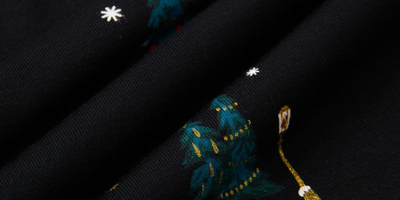 Close-up of a black fabric with a festive holiday print featuring snowmen, snowboards, decorated Christmas trees, and snowflakes.