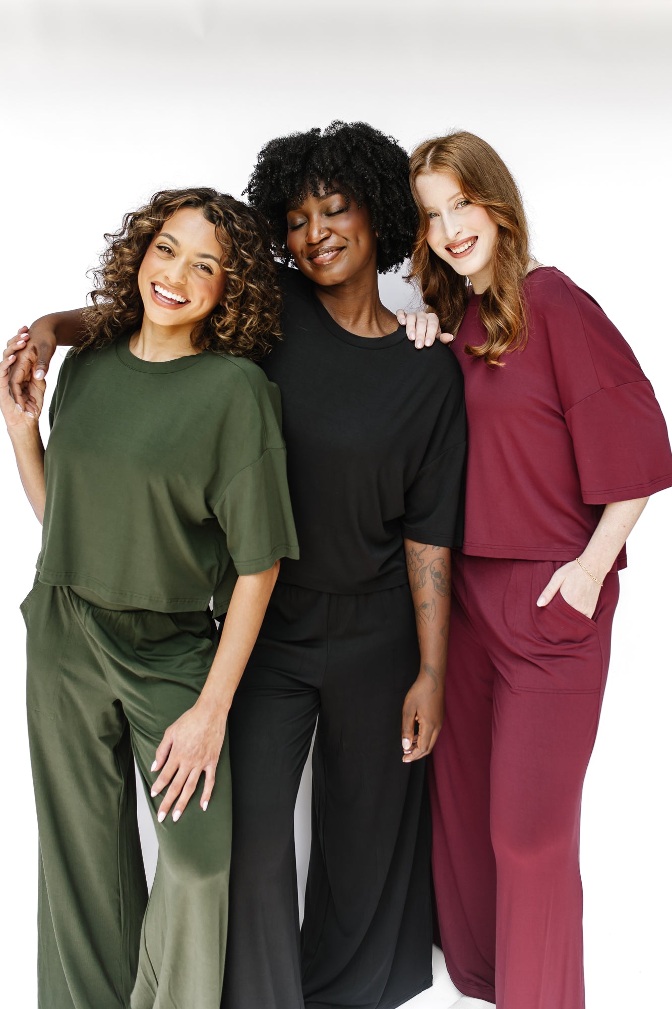 Models wearing the Women's Short Sleeve Tees and matching wide leg pants in Fir, Midnight and Burgundy