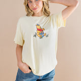 Woman wearing a yellow t-shirt with a cartoon character on a beige background