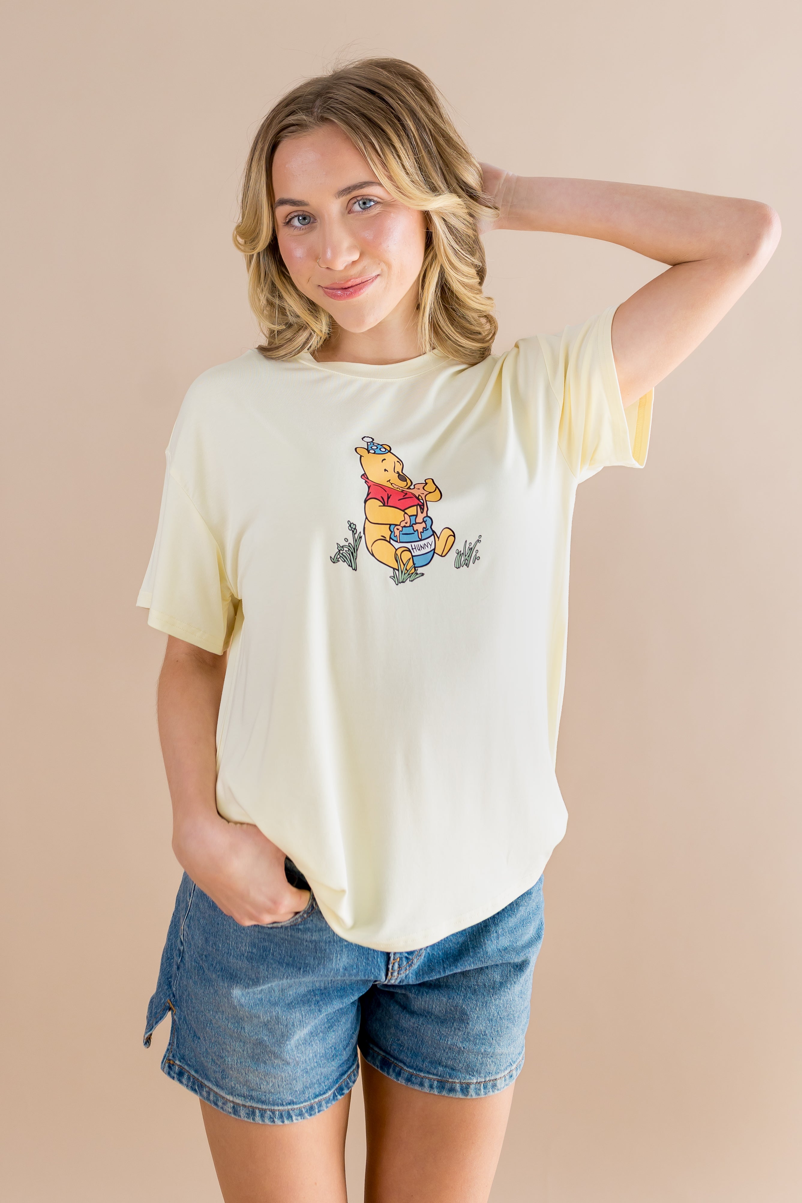 Woman wearing a yellow t-shirt with a cartoon character on a beige background