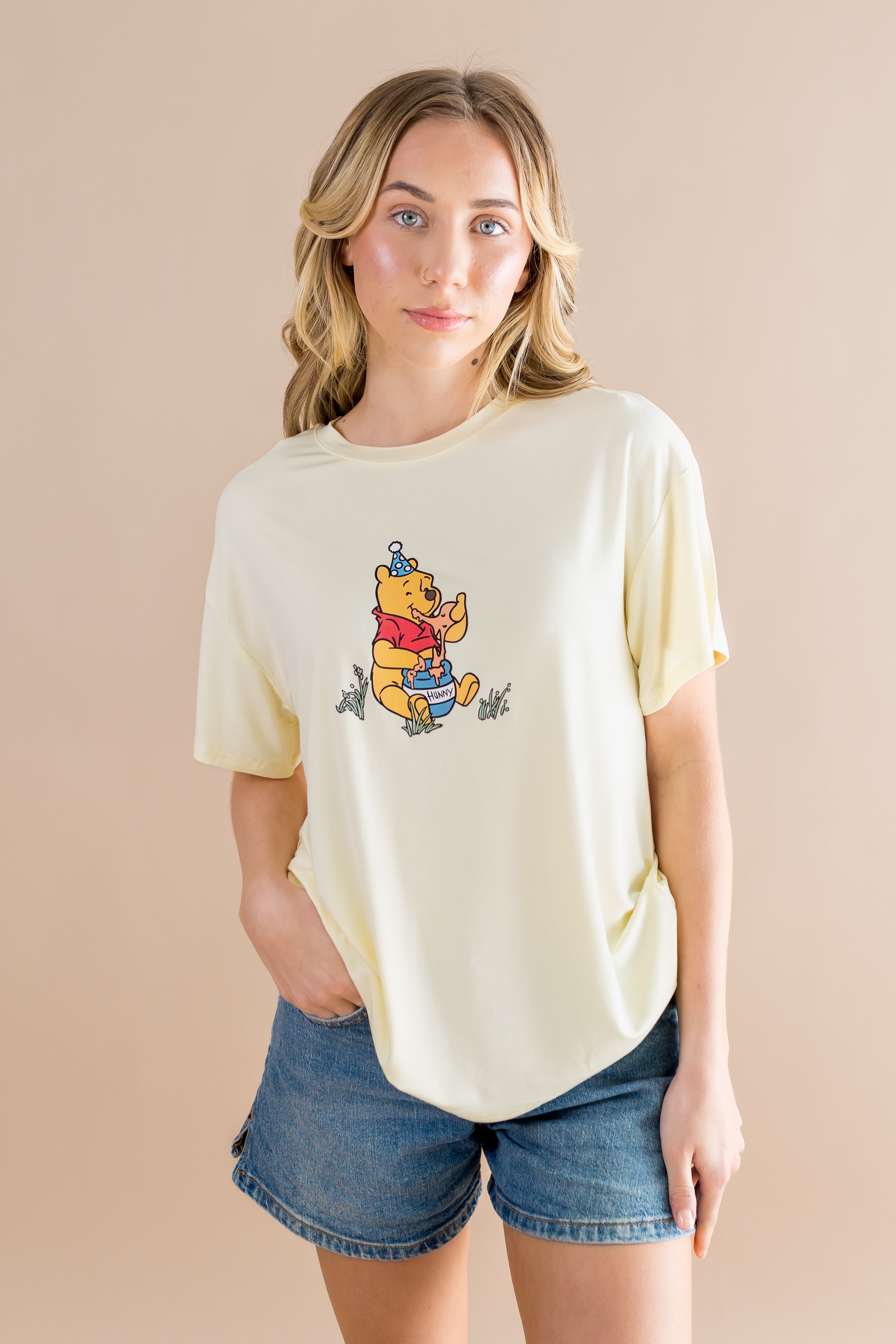 Woman wearing a yellow-colored t-shirt with a Winnie the Pooh character on a beige background ::: Model is 5'7" wearing size S ///