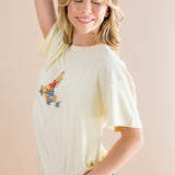 Woman wearing a cream-colored t-shirt with a graphic design on a beige background