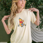 Woman wearing yellow graphic tee with winnie the pooh birthday party graphic ::: Model is 5'7" wearing size S ///