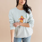 Woman wearing a light blue sweatshirt with a cartoon character on a beige background