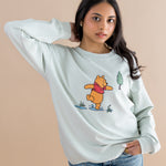 Person wearing a light blue sweatshirt with a cartoon character on a beige background
