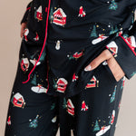 Womans bottom half with her hands in her pocket wearing long sleeve pajama set in winter wonderland