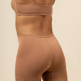 Model showcasing the back side of the Women's Boxer in Latte and the straps of the Cross Front Bralette 