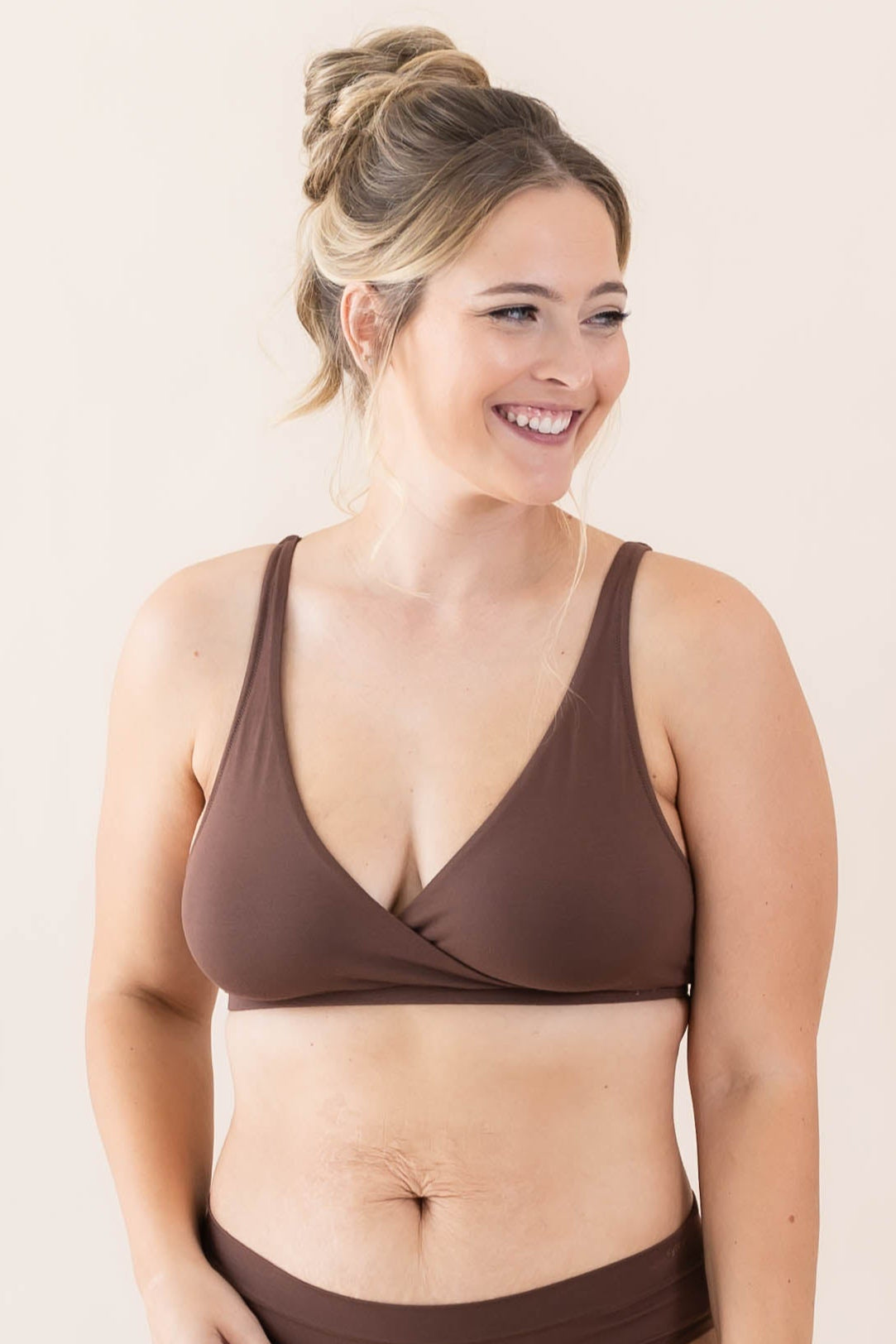 Woman wearing a brown bralette set on a plain background