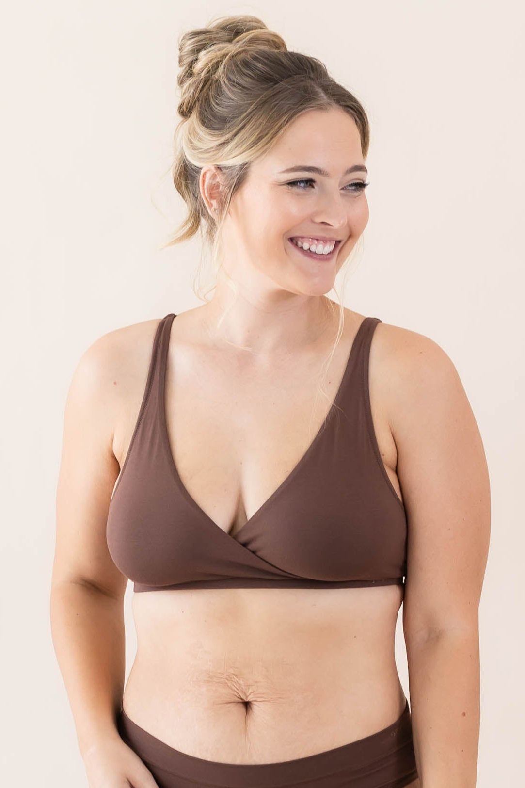 Woman wearing a brown bralette set on a plain background