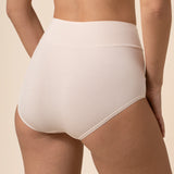 Person wearing cream high-waisted underwear on a beige background