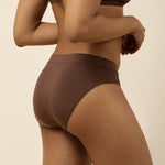 Person wearing a brown brief underwear set on a beige background