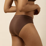 Person wearing a brown brief underwear set on a beige background