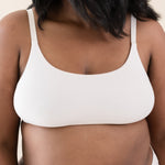 Woman wearing scoop neck bralette and matching underwear in a cream color