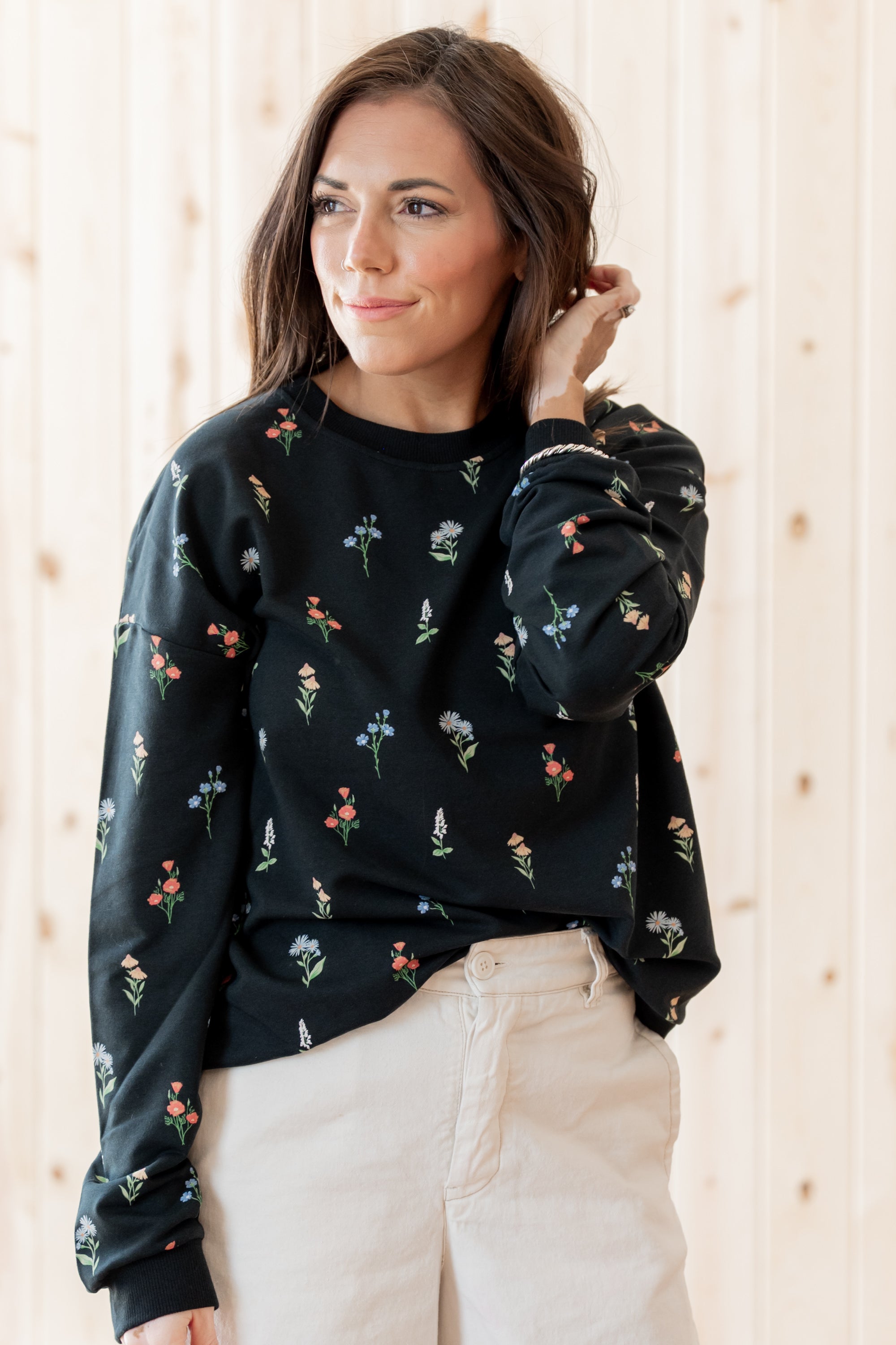 Model standing in front of a light birch back ground while modeling the Women's Sweatshirt in Midnight Wildflower paired with light bottoms
::: Model is 5'3" wearing size S ///