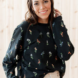 Smiling model wearing the Women's Sweatshirt in Midnight Wildflower paired with a light paired bottoms