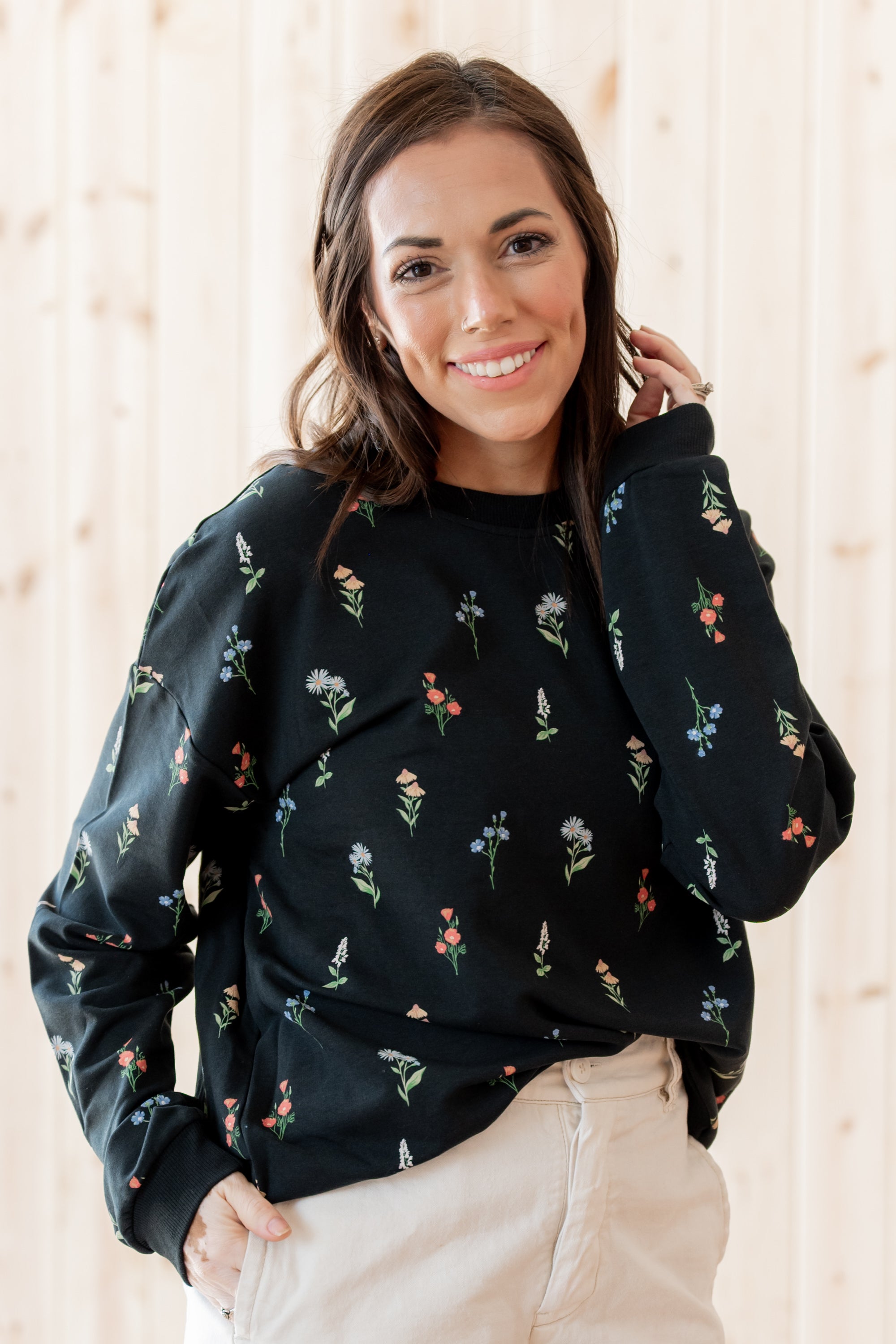 Smiling model wearing the Women's Sweatshirt in Midnight Wildflower paired with a light paired bottoms