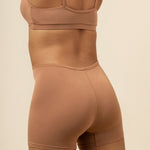 Model showcasing the back side of the Women's Boxer in Latte and the straps of the Cross Front Bralette 

