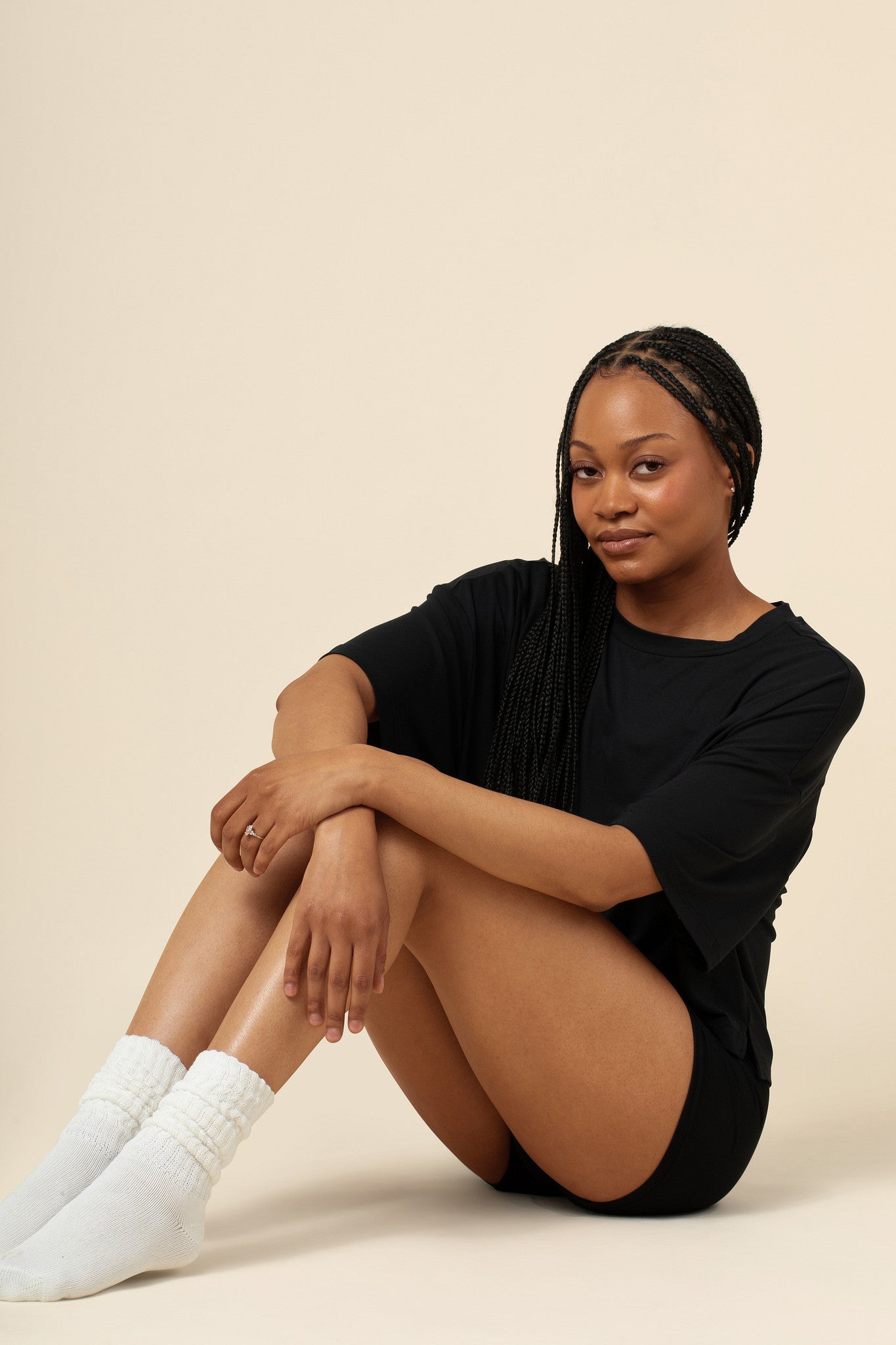 Model posing with knees up and arms crossed over knees while wearing the Women's Boxer in Midnight paired with the Women's Tee in Midnight 