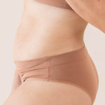 Brown cheeky underwear worn by a person on a light pink background