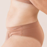 Brown cheeky underwear worn by a person on a light pink background