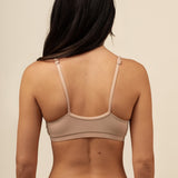Woman wearing a beige bra and underwear set against a beige background