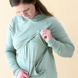 Female lifting up the front material in the Women's French Terry Nursing Hoodie in Thyme