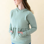 Model wearing the Women's French Terry Nursing Hoodie in Thyme with both hands in the pocket