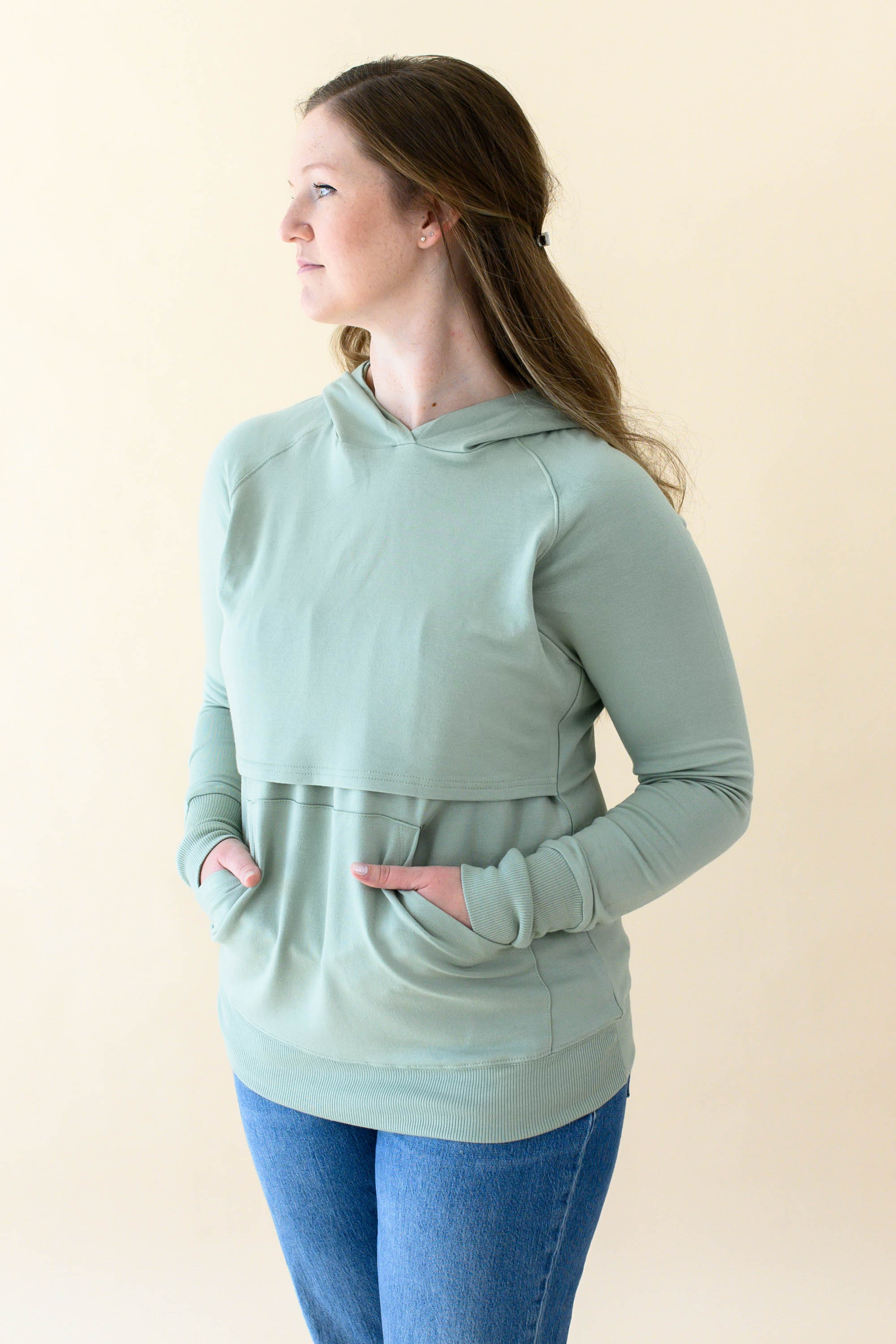Model wearing the Women's French Terry Nursing Hoodie in Thyme with both hands in the pocket